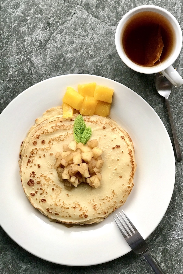 Stack of pancakes with apple-cinammon topping and cup of black tea