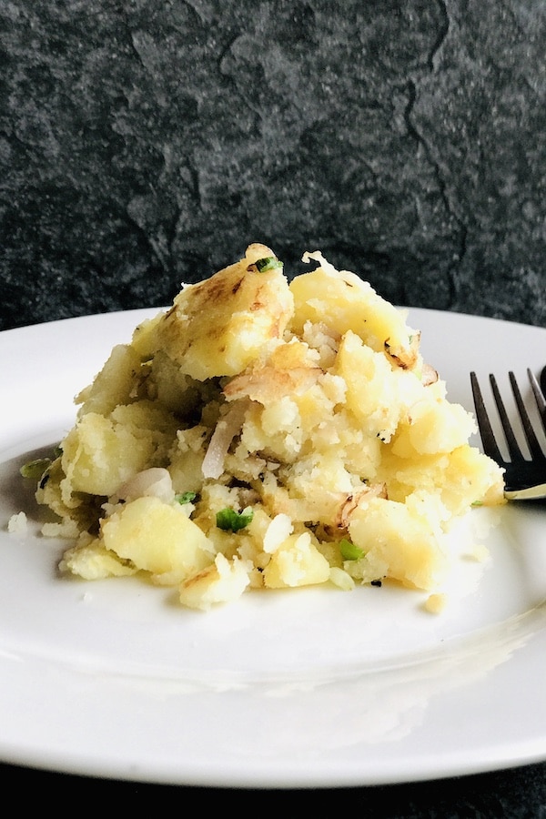 A white round plate with smashed fried potatoes