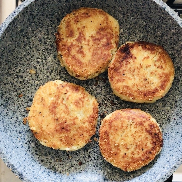 A mottled frying pan with 4 golden brown yam patties