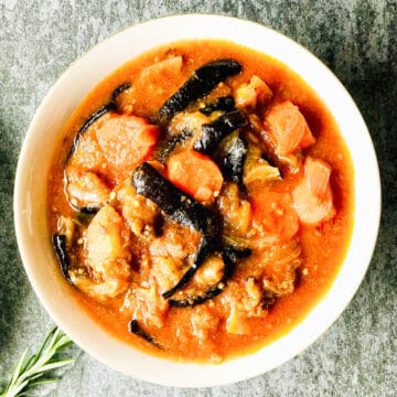 White bowl of lamb stew with carrots and aubergines