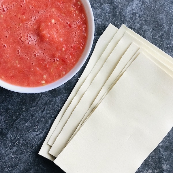Blended tomatoes in white round ceramic bowl, and lasagne sheets
