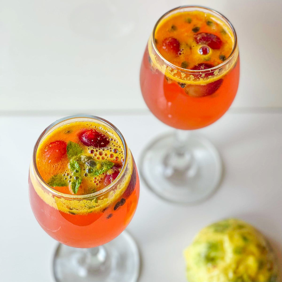 two wine glasses of hibiscus passion fruit chiller on a white background