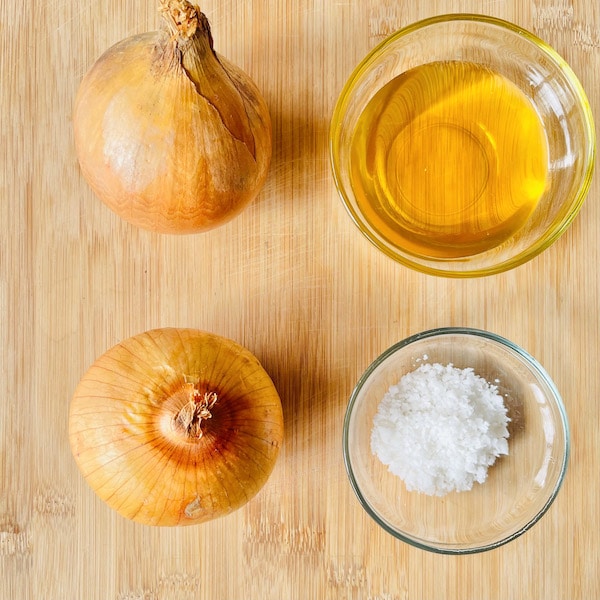 2 onions, vegetable oil in a round glass bowl, and sea salt in a round, glass bowl