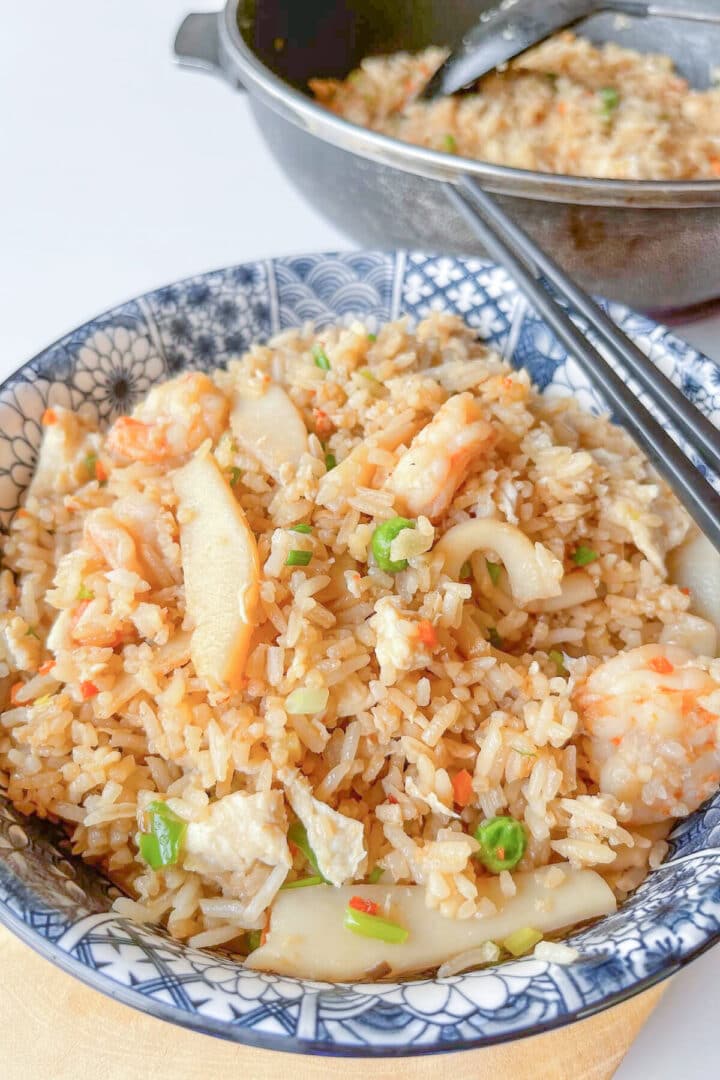 Seafood fried rice in a blue and white obowl with black chopsticks