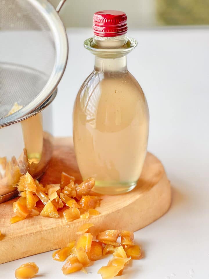 Ginger syrup in a bottle with ginger pieces at the bottom