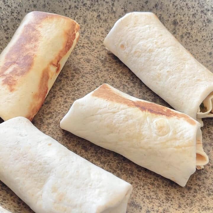 Four chicken wraps tortillas in a pan.