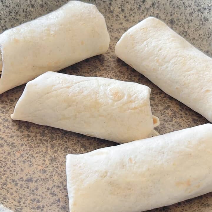 Four chicken wraps tortillas in a pan.