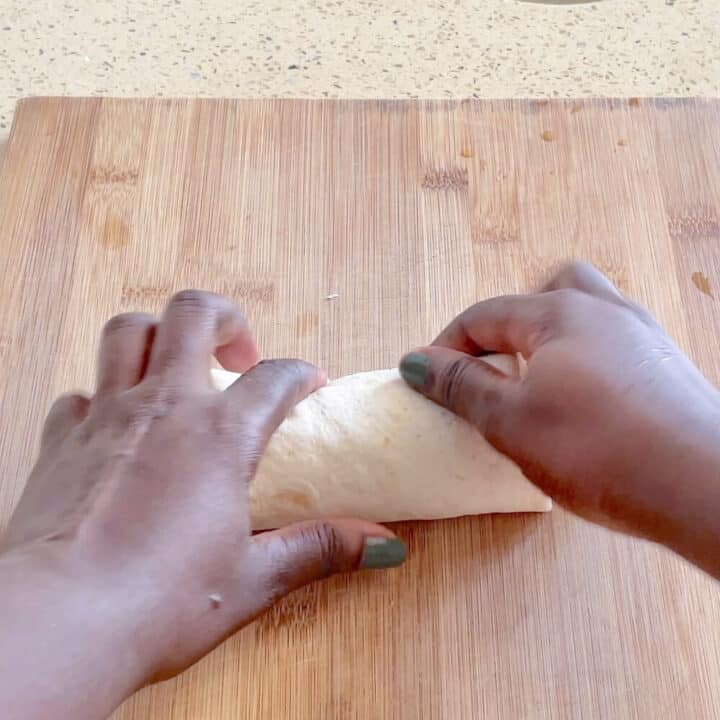 Tortilla being wrapped on a wooden board.