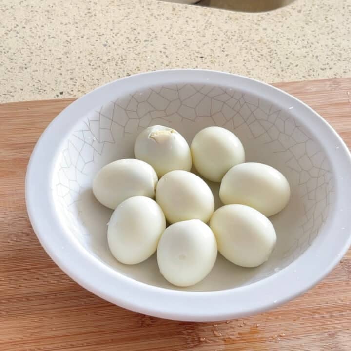 8 peeled eggs in a white round plastic plate.