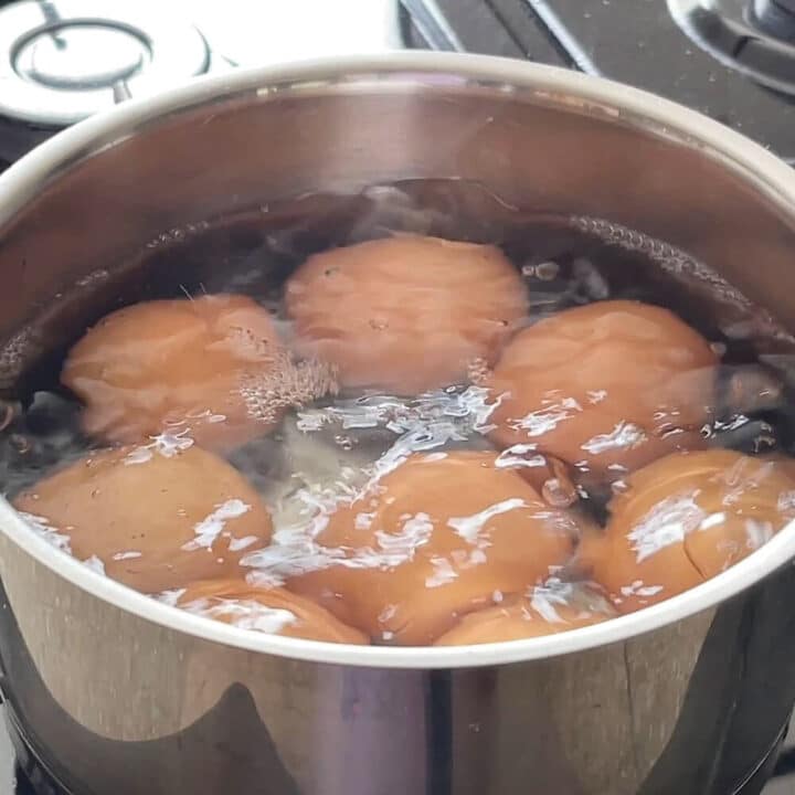 8 brown eggs boiling in a saucepan.