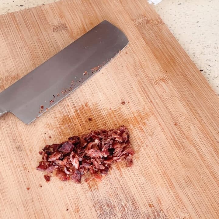 Chopped fried bacon on a wooden board.