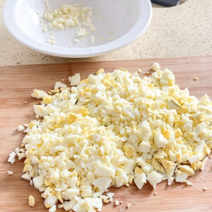 Chopped eggs on a wooden board.