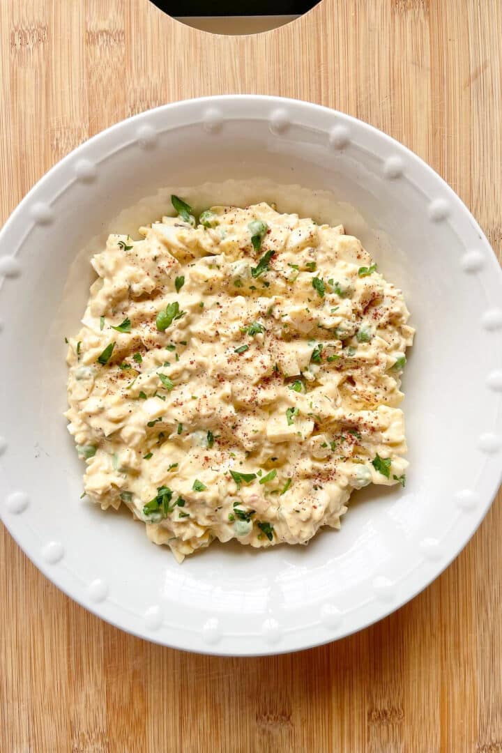 Egg salad in a round white ceramic bowl.