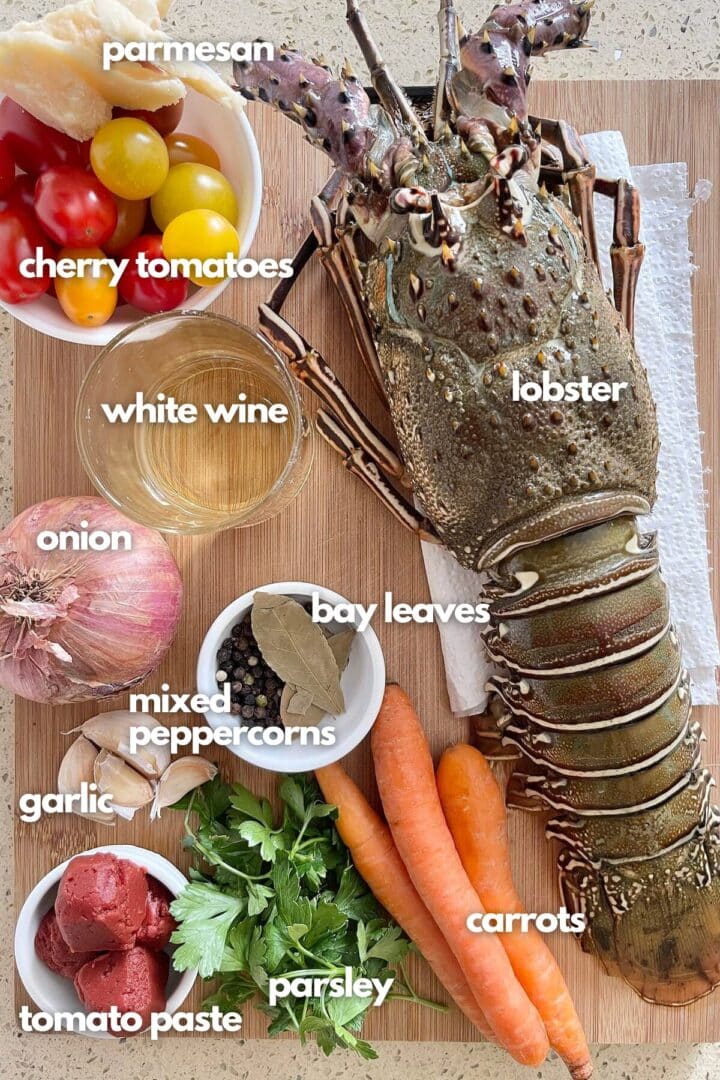 ingredients for lobster pasta: lobster, cherry tomatoes, carrots, tomato paste, parmesan, onions, peppercorns and bay leaves.