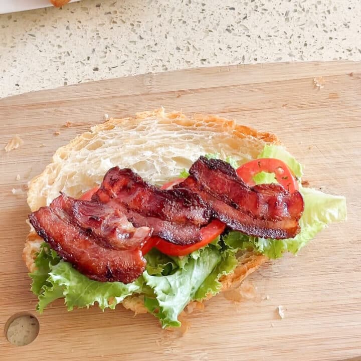 Fried bacon strips on sliced croissant.