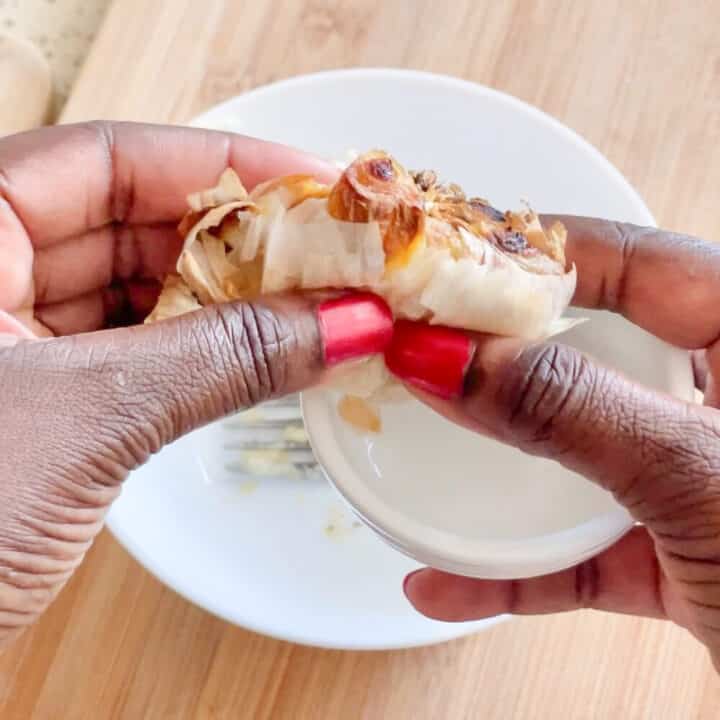Roasted garlic squeezed into a white round ceramic bowl.