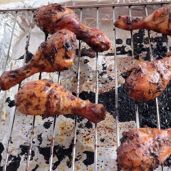 Grilled chicken drumsticks on a metal rack.