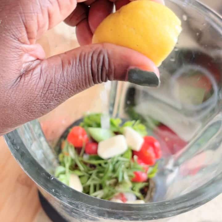 Lime squeezed into a glass blender with herbs and spices for marinade.