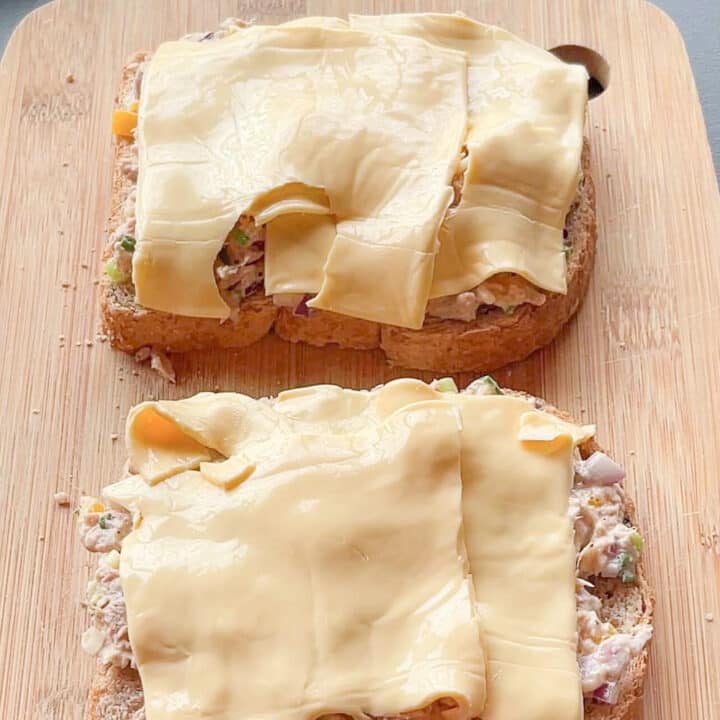 Bread with sliced cheese on top on a wooden board.