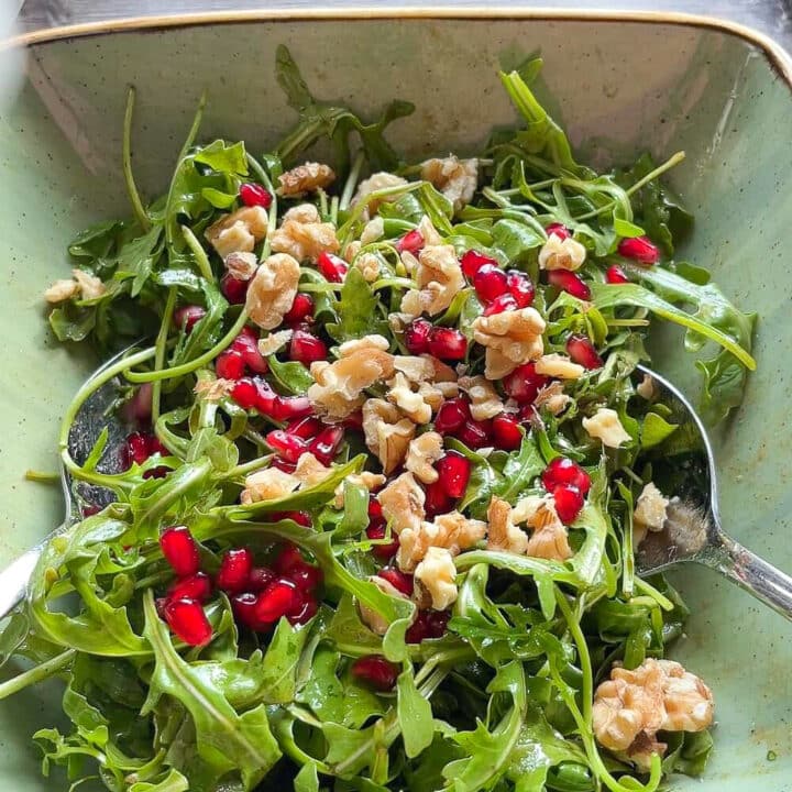 Arugula salad with pomegranate seeds and chopped walnuts.
